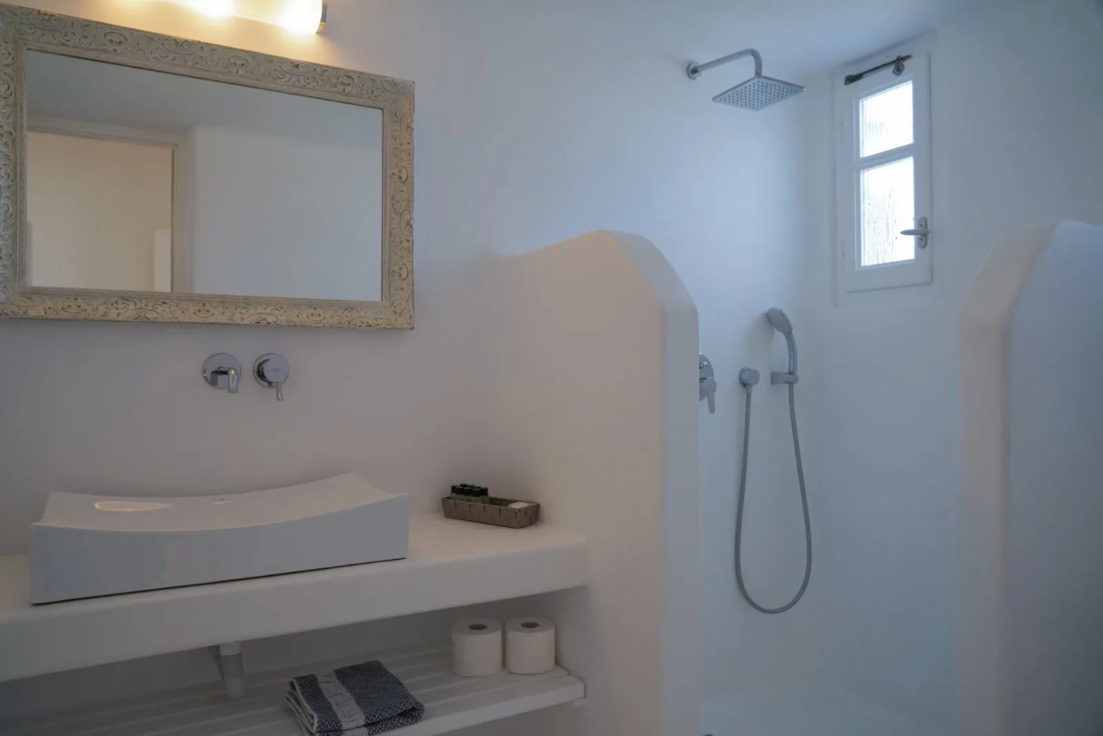 A bathroom with a sink, mirror, and shower.