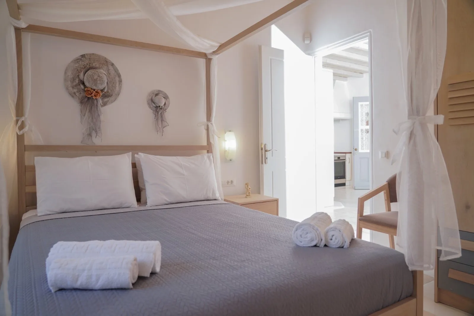 A bedroom with a neatly made bed and sheer curtains around the frame.