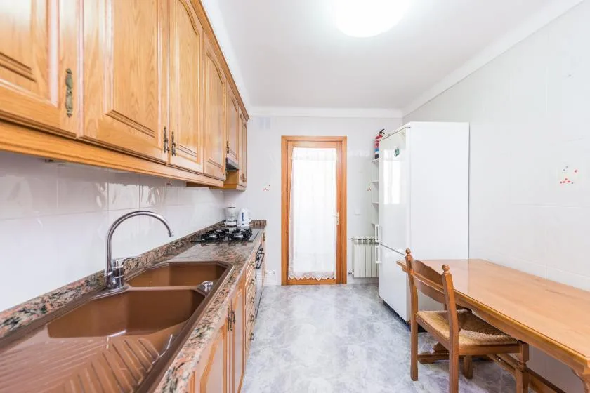 A kitchen with wooden cabinets, a sink, and a dining table.
