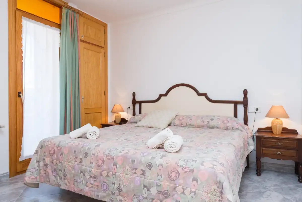 A bedroom with a patterned bedspread, wooden headboard, and bedside lamps.