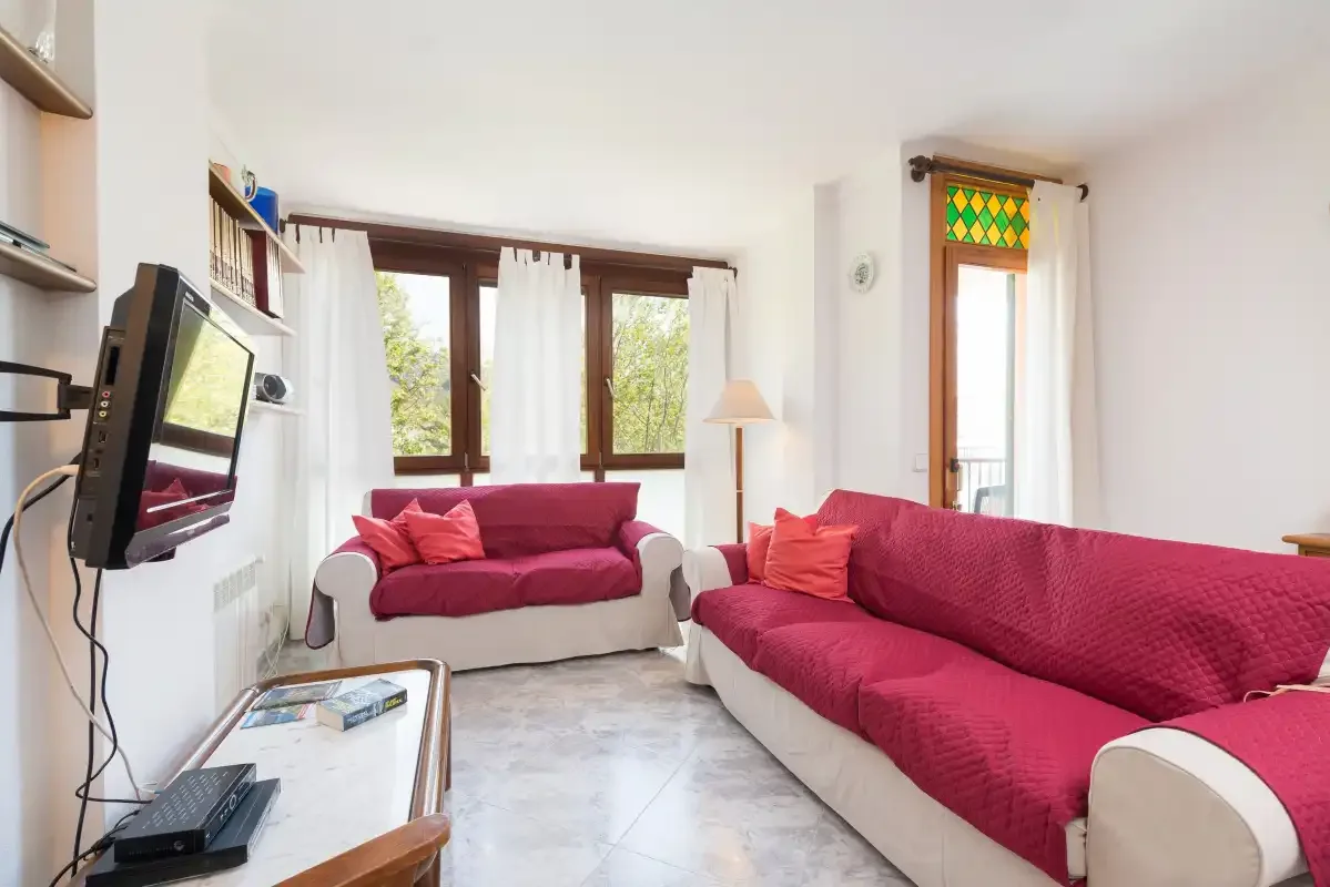 A living room with seating, a television, and windows.
