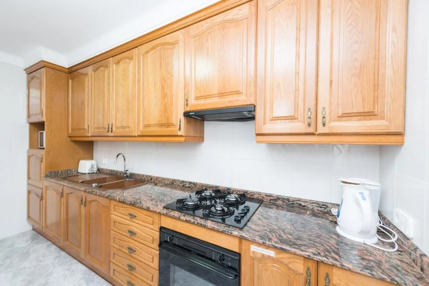 A kitchen with wooden cabinets, a countertop, and a cooktop.