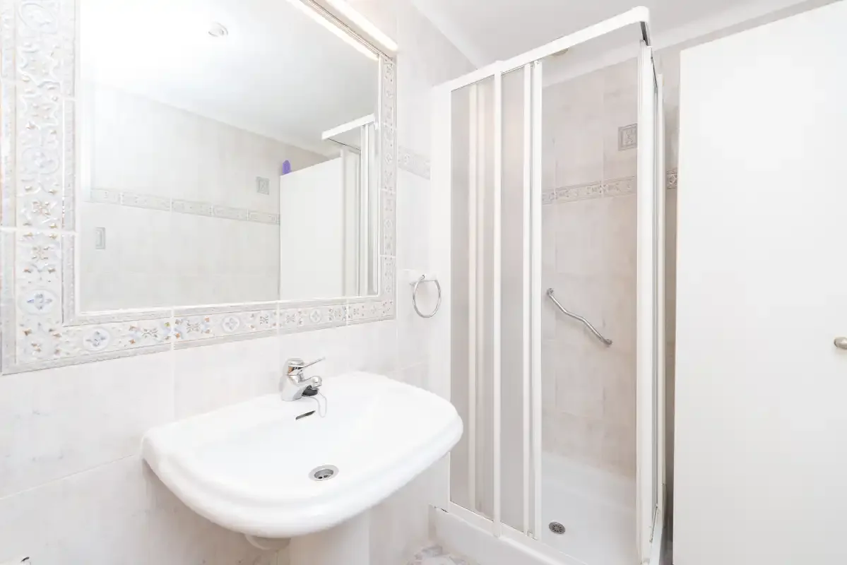 A bright bathroom with a sink and shower.