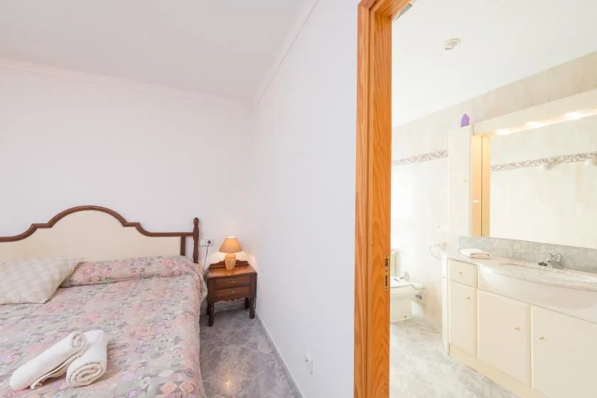 A bedroom with a patterned bedspread and an adjoining bathroom.