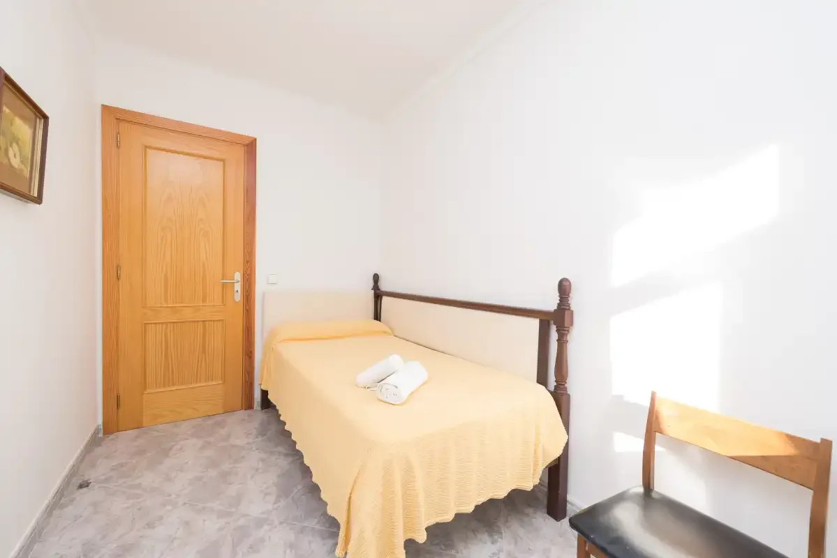 A bedroom with a single bed and a wooden door.