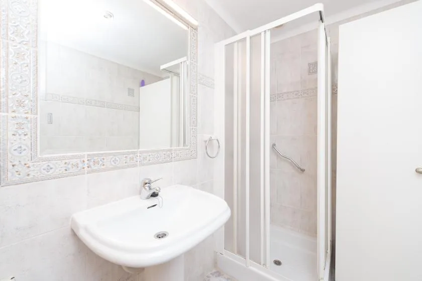 A bright bathroom with a wall-mounted sink and a glass shower.