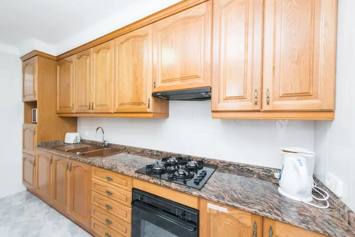 A kitchen with wooden cabinets, a countertop, and a cooktop.