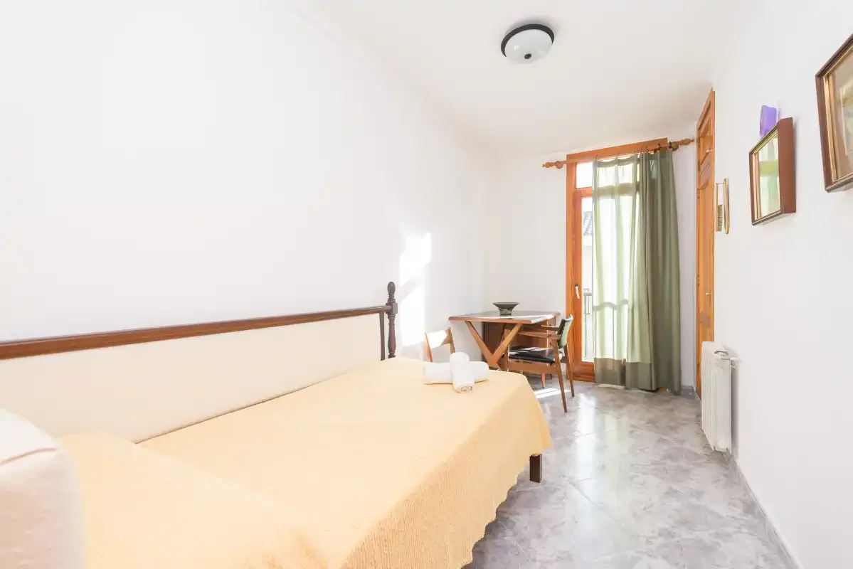 A bedroom with a bed and a curtained window.