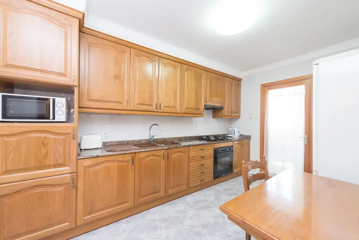 A kitchen with wooden cabinets, a built-in oven, and a dining table.
