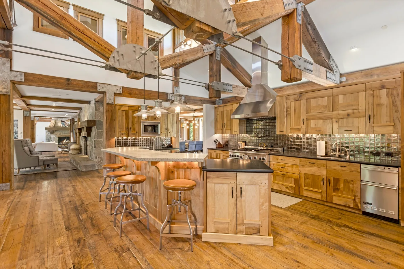 A spacious kitchen with a central island, bar seating, and exposed wooden beams.