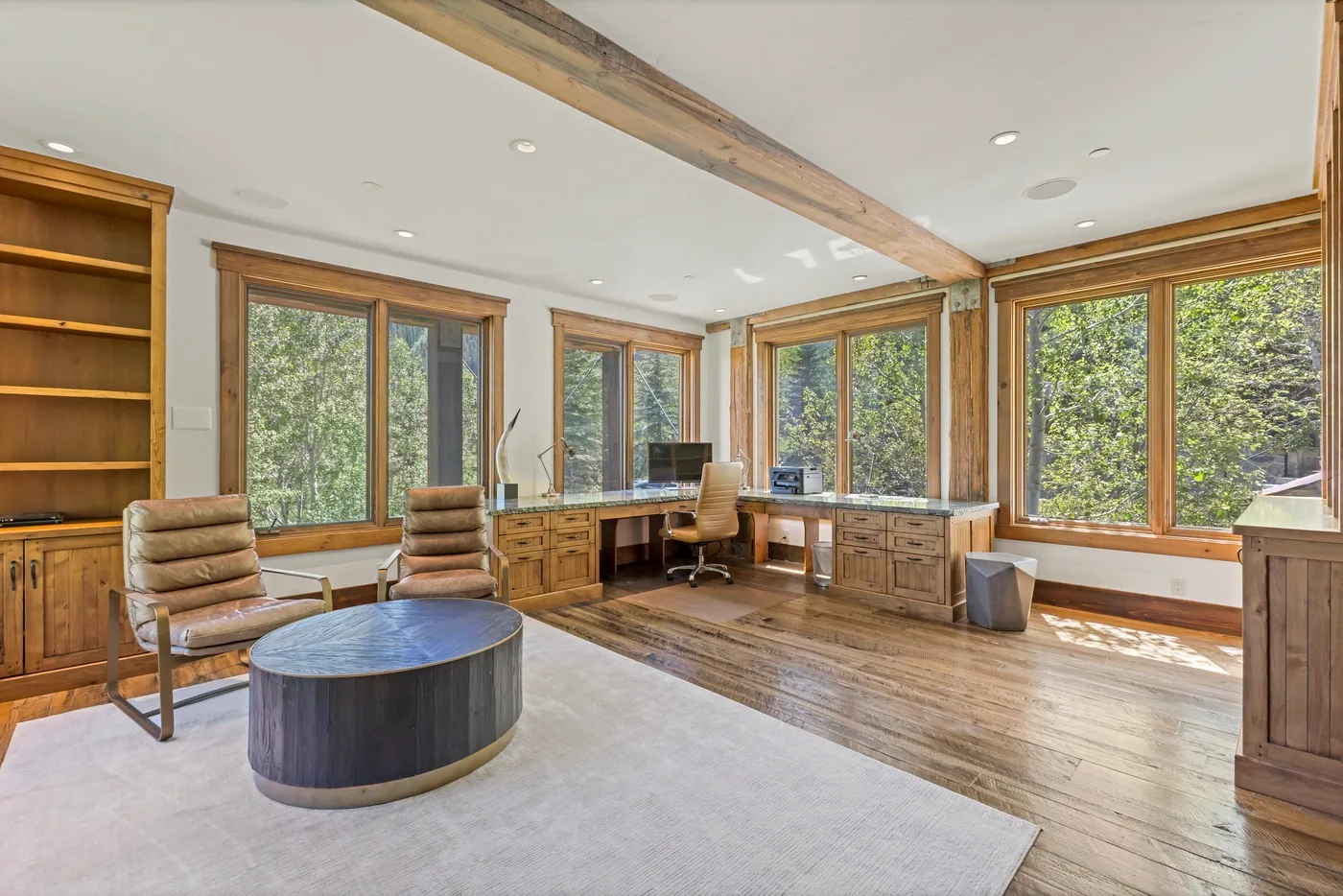 A bright home office with wood cabinetry, a desk, and large windows.