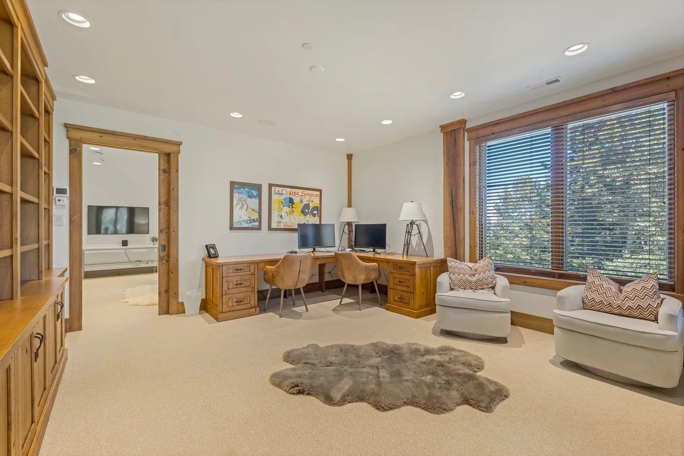 A bright home office with a desk and seating beside a large window.