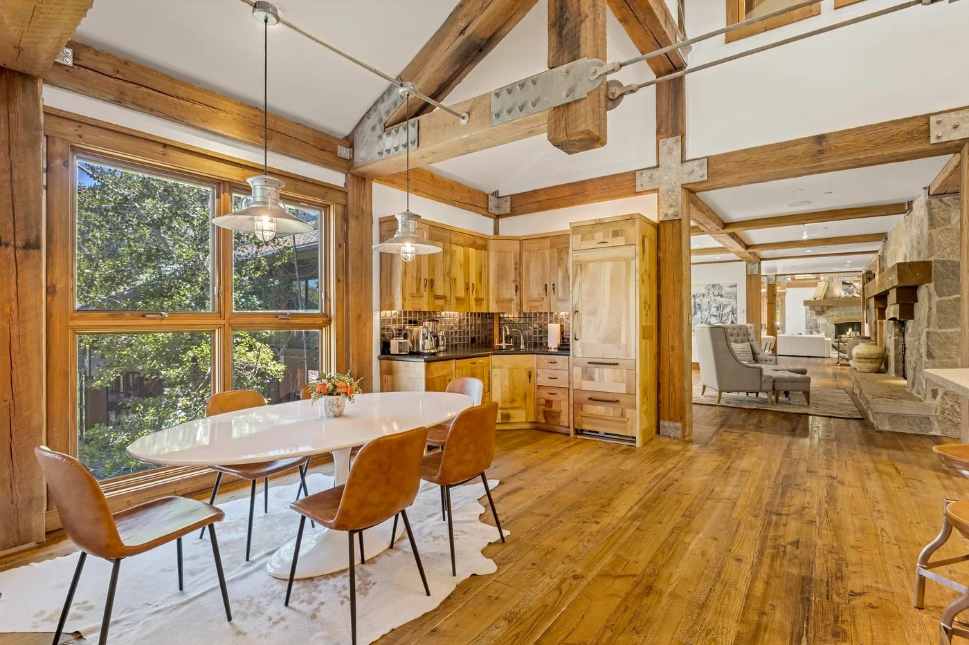 A bright dining area with a white table beside large windows and a kitchen.