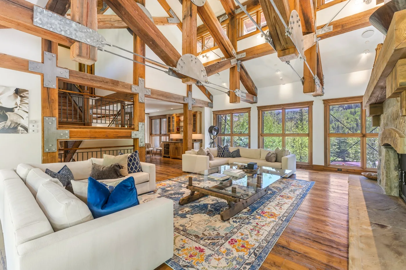 A spacious living room with seating, a patterned rug, and large windows.