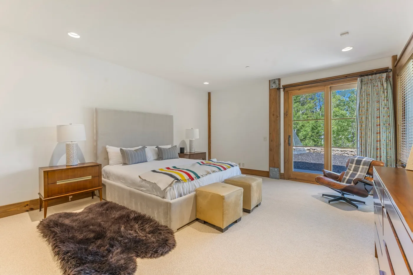 A spacious bedroom with a bed, bedside tables, and glass doors opening to a balcony.