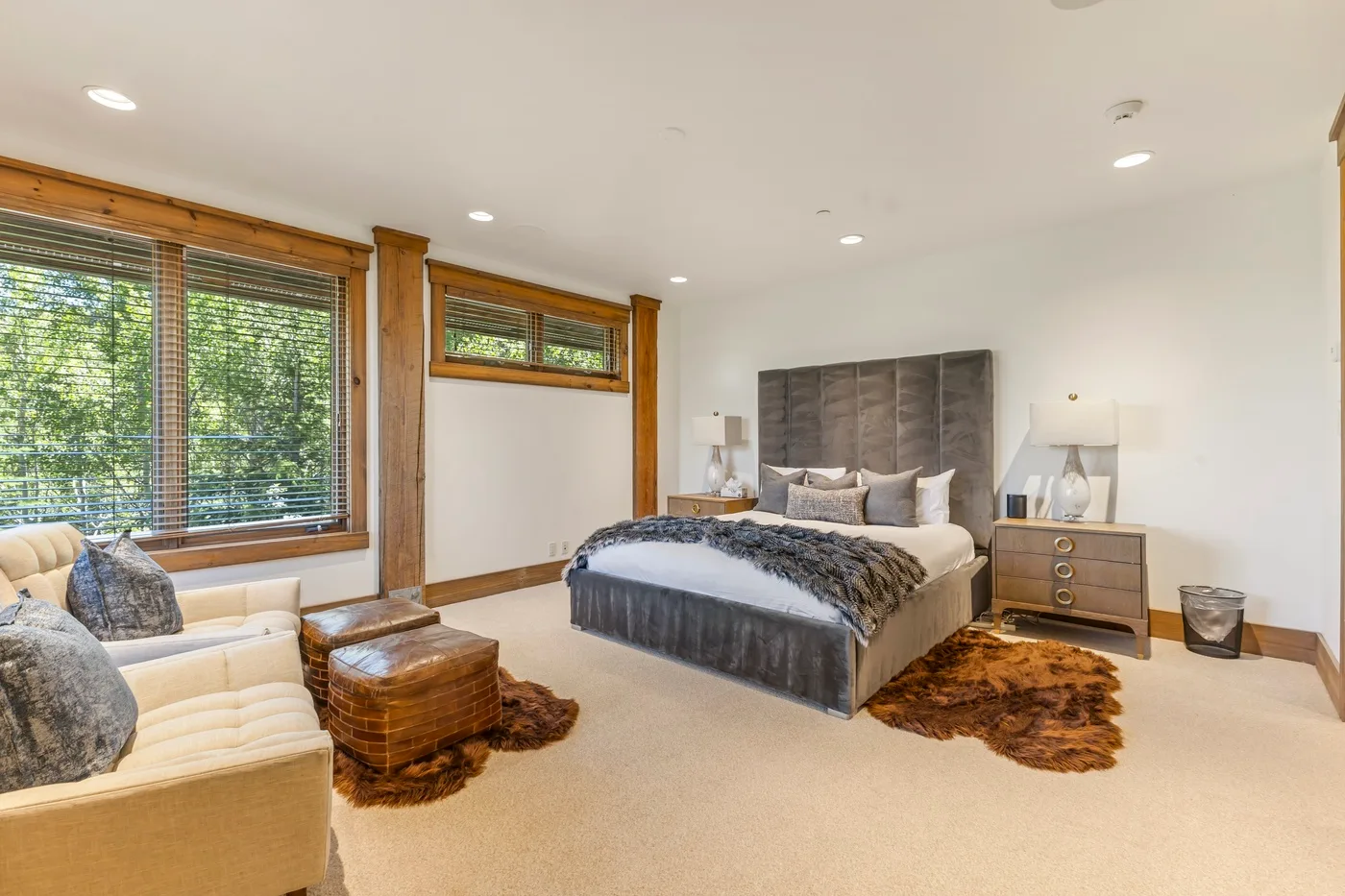 A bedroom with a large bed, bedside tables, and a seating area by the windows.