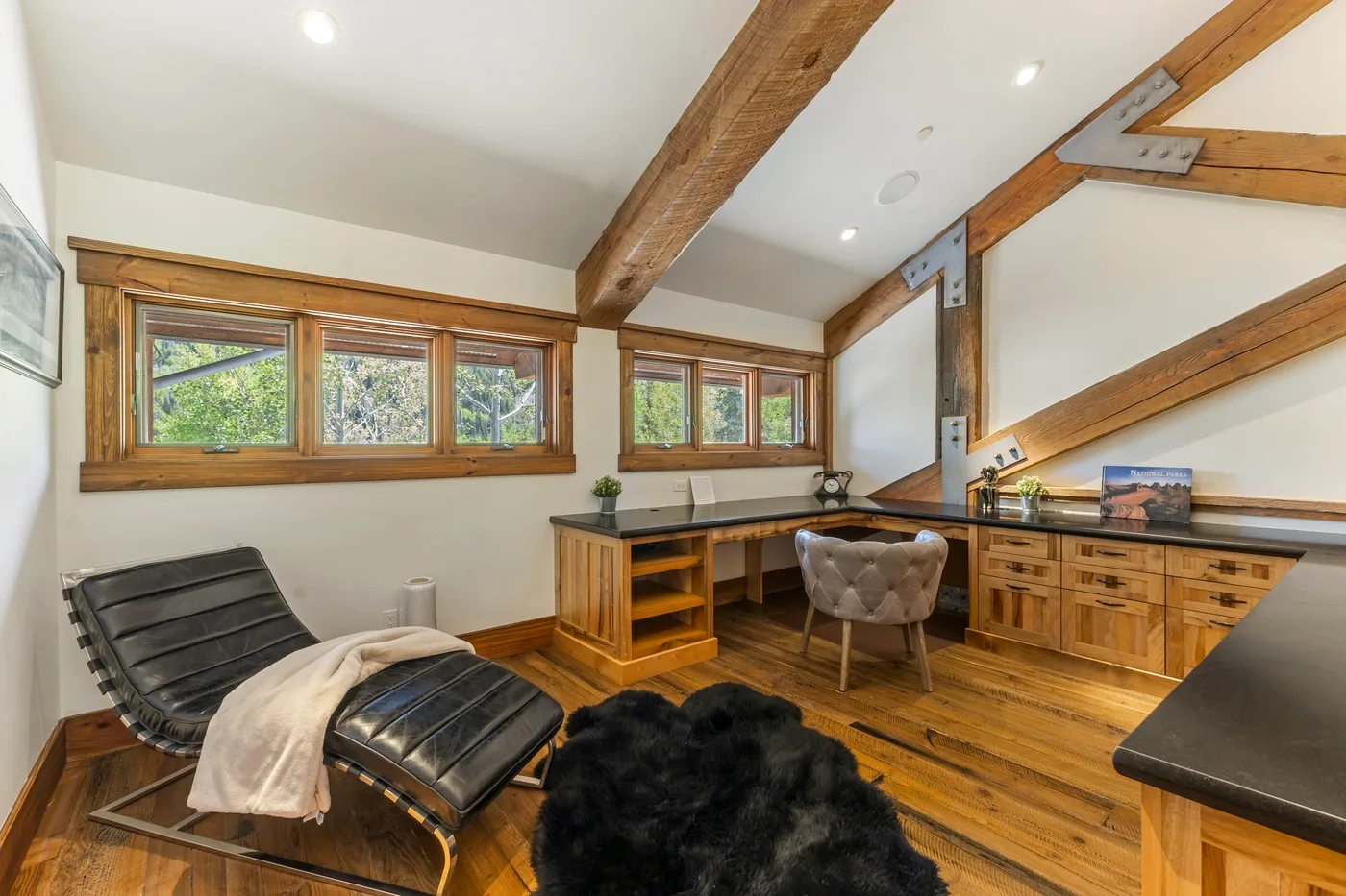 A wood-paneled home office with a desk beneath exposed ceiling beams.