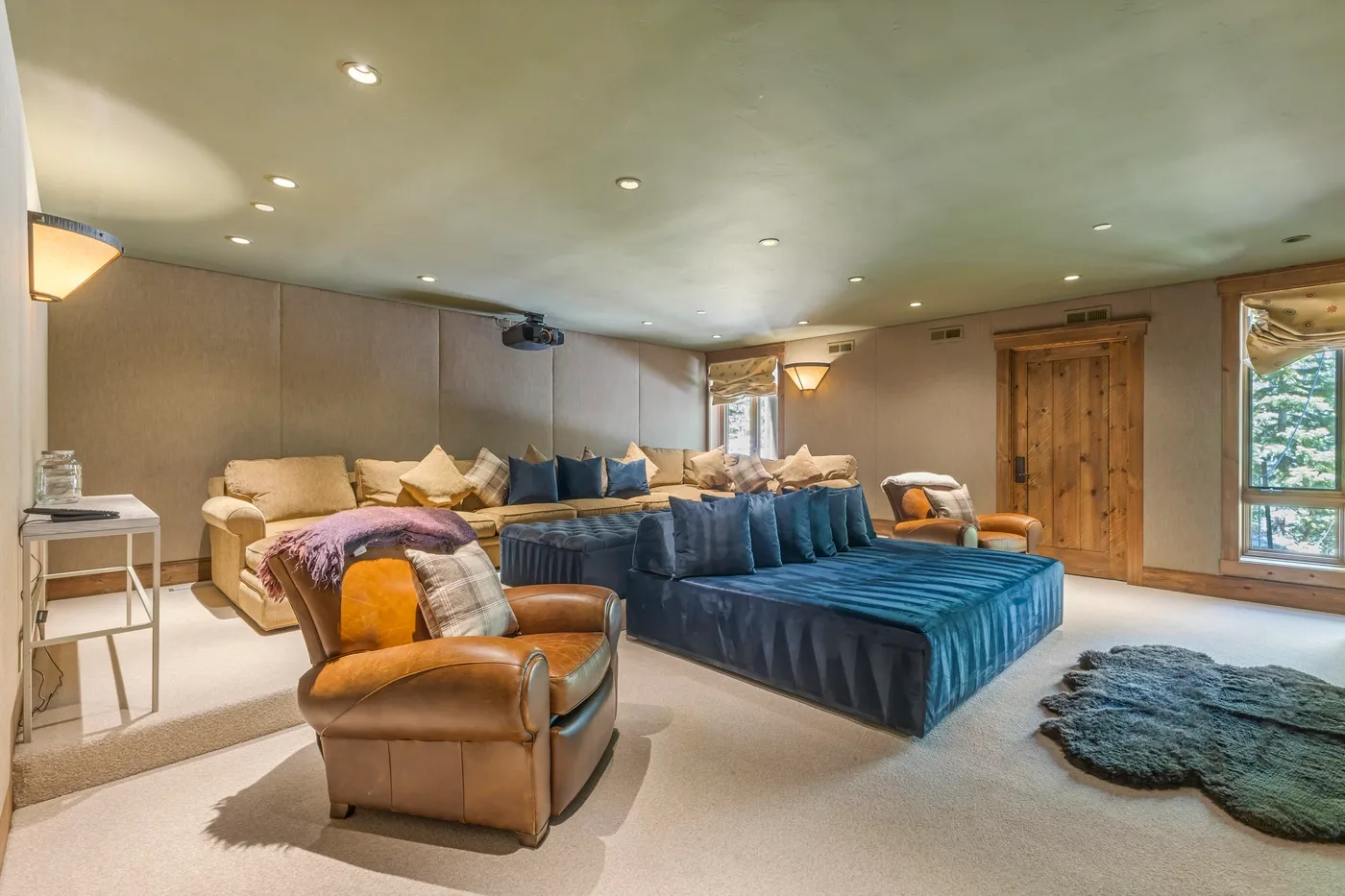 A bedroom with a blue bed, seating, and a wooden door.