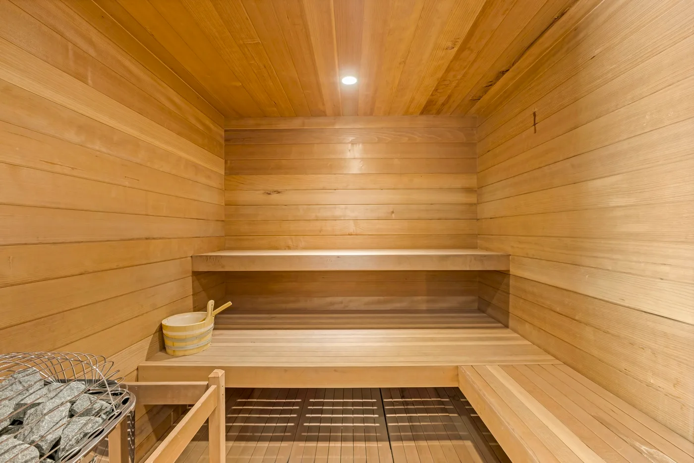 A wood-paneled sauna room with tiered benches and a heater.