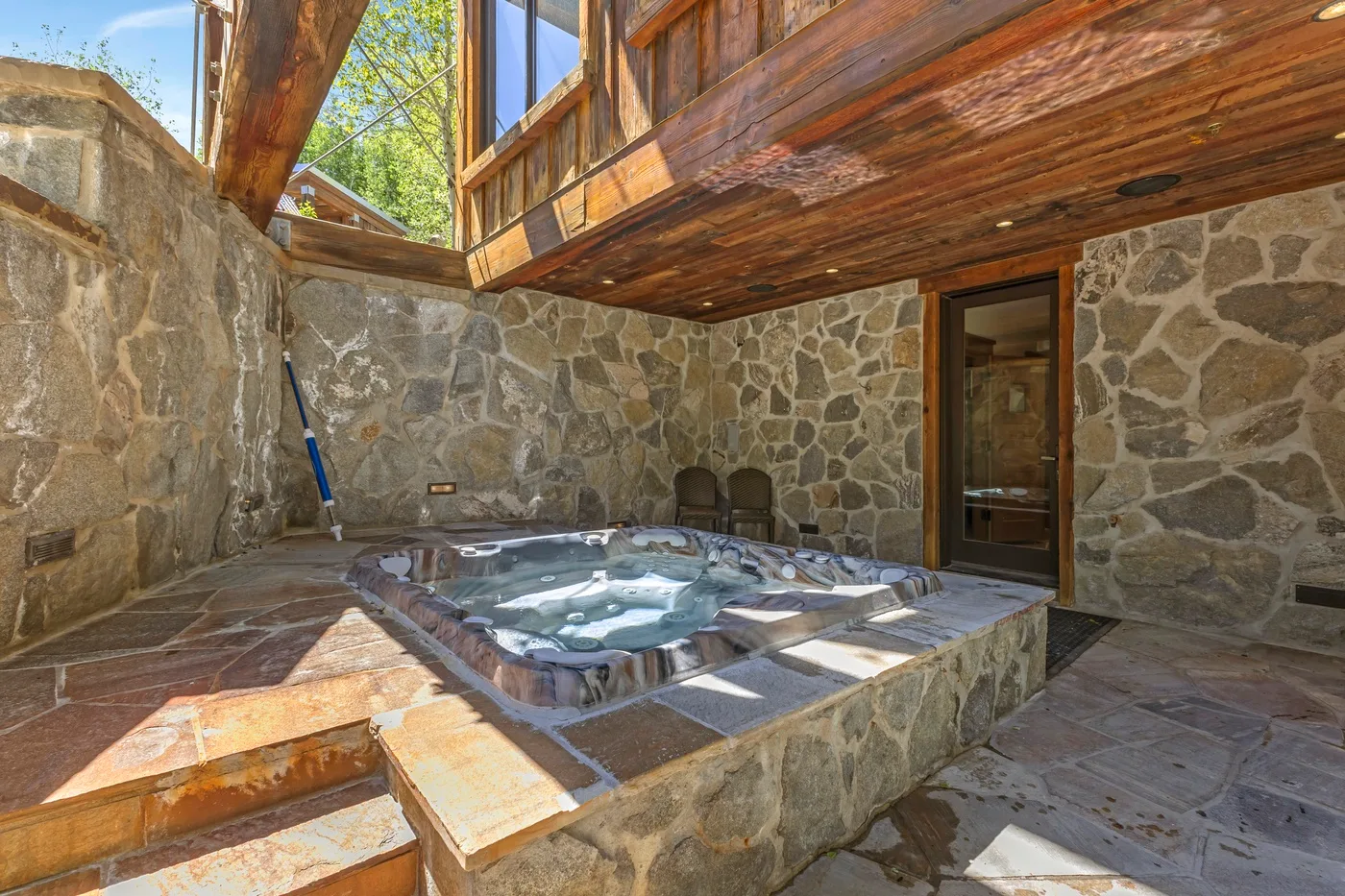 A stone courtyard with a small outdoor pool beneath a wooden overhang.