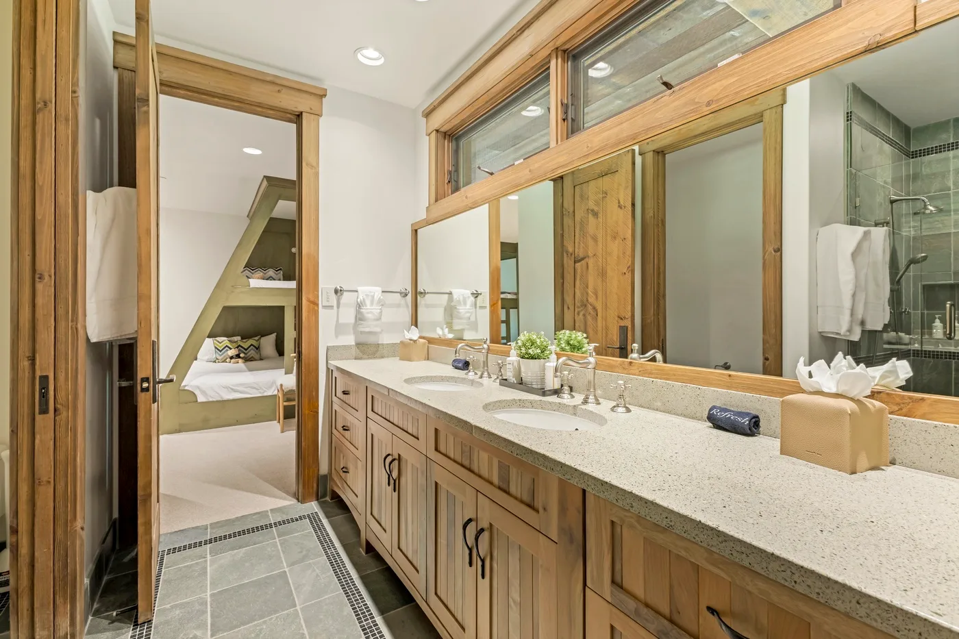 A bathroom vanity with a long countertop and a doorway to the bedroom.