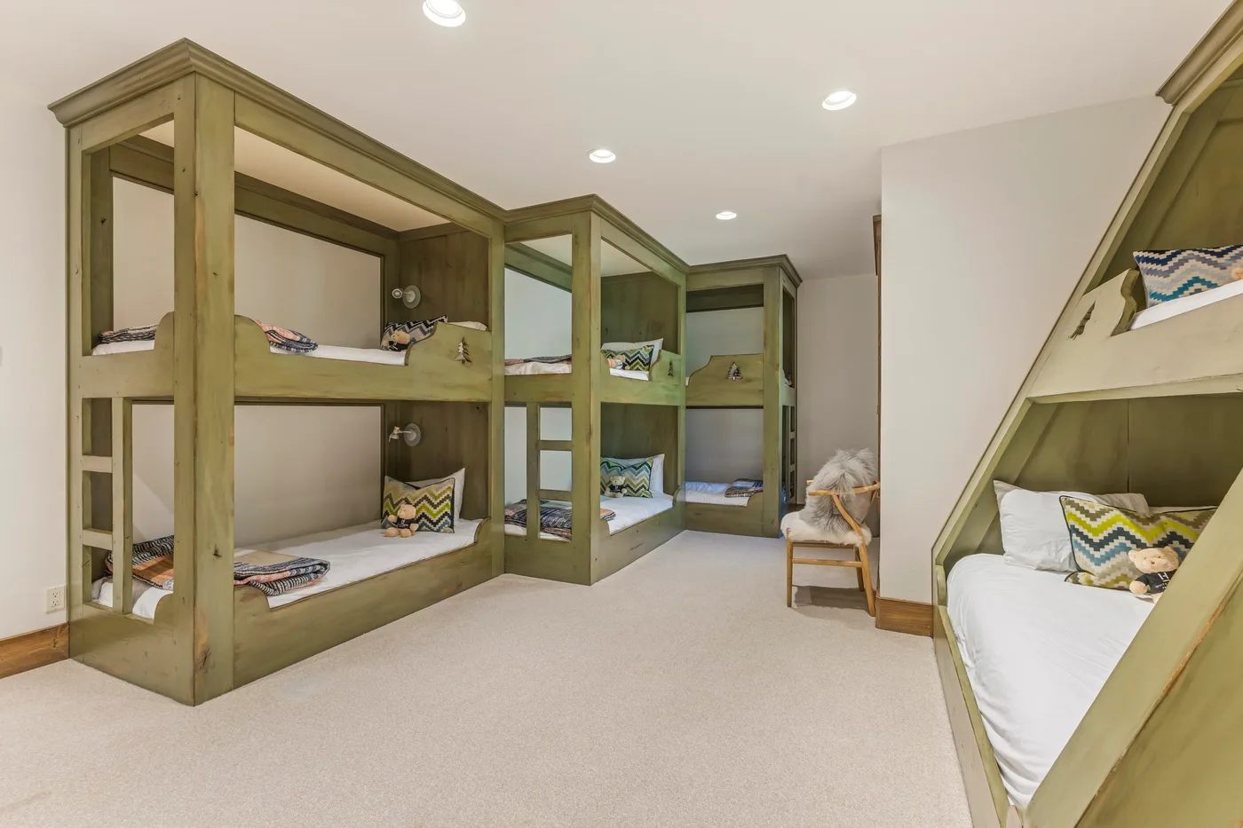 A bedroom with built-in bunk beds, colorful pillows, and a carpeted floor.