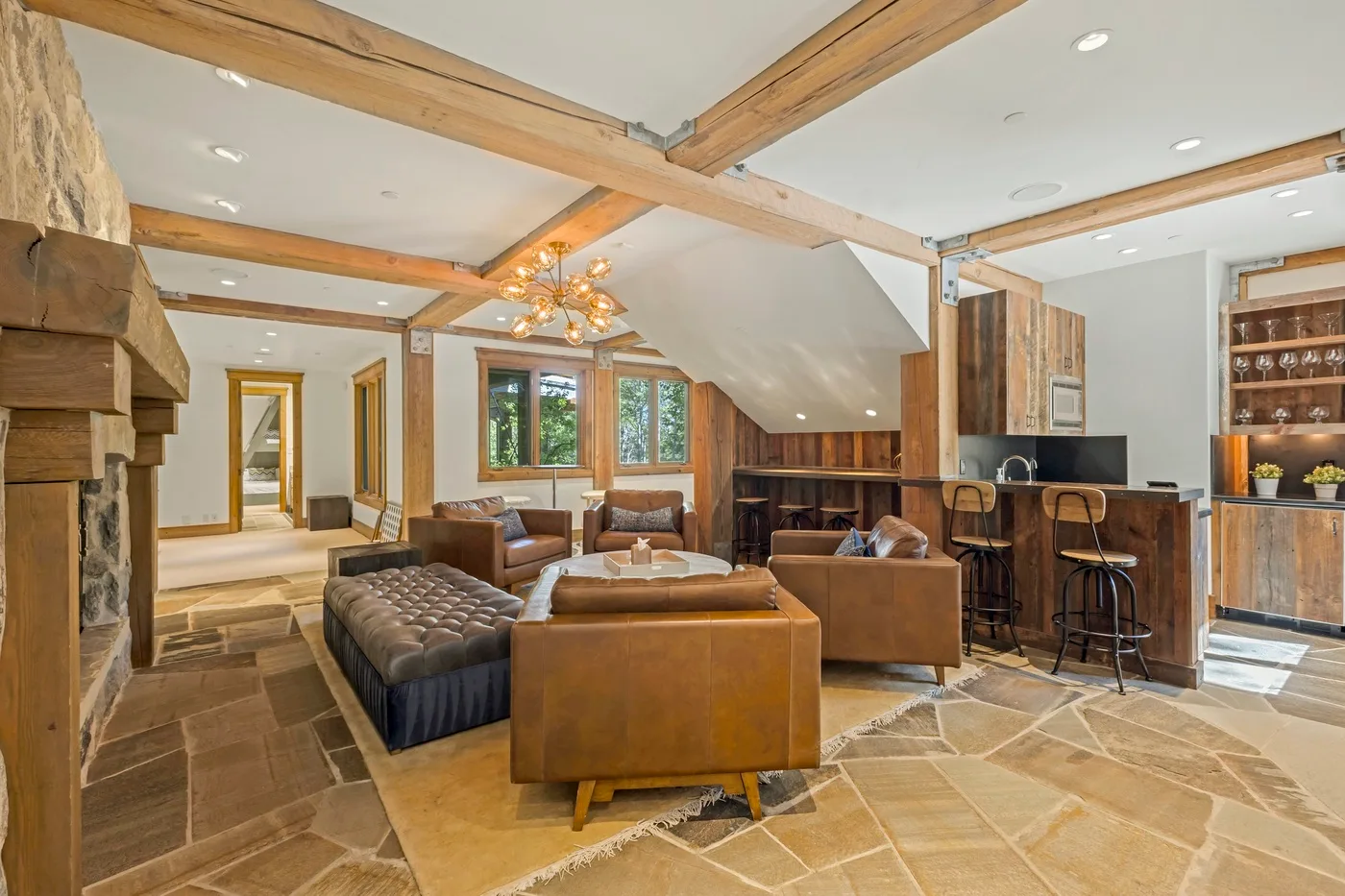 A spacious living room with seating, exposed wooden beams, and a kitchen counter.