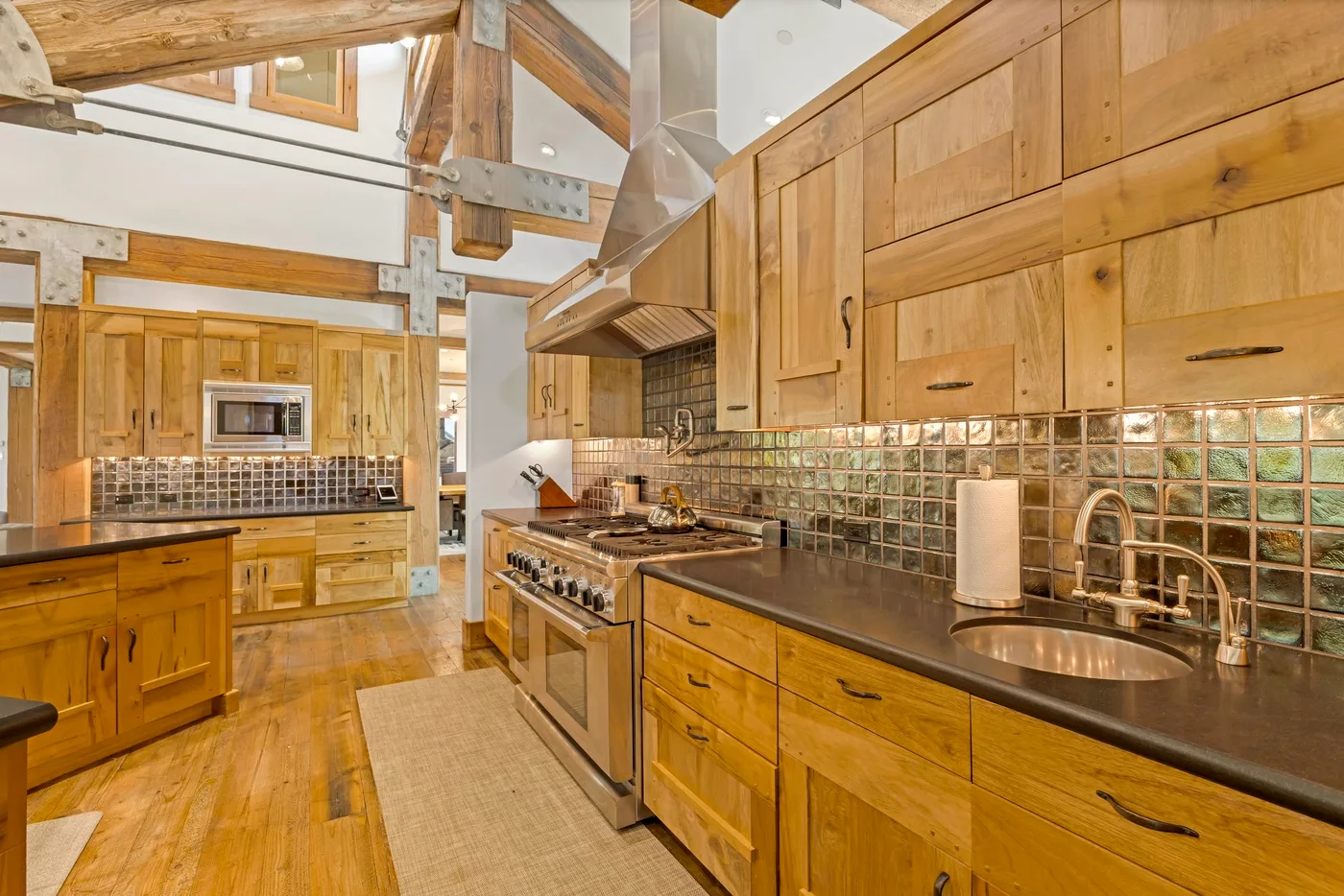 A warm wood kitchen with long counters, cabinetry, and a tiled backsplash.
