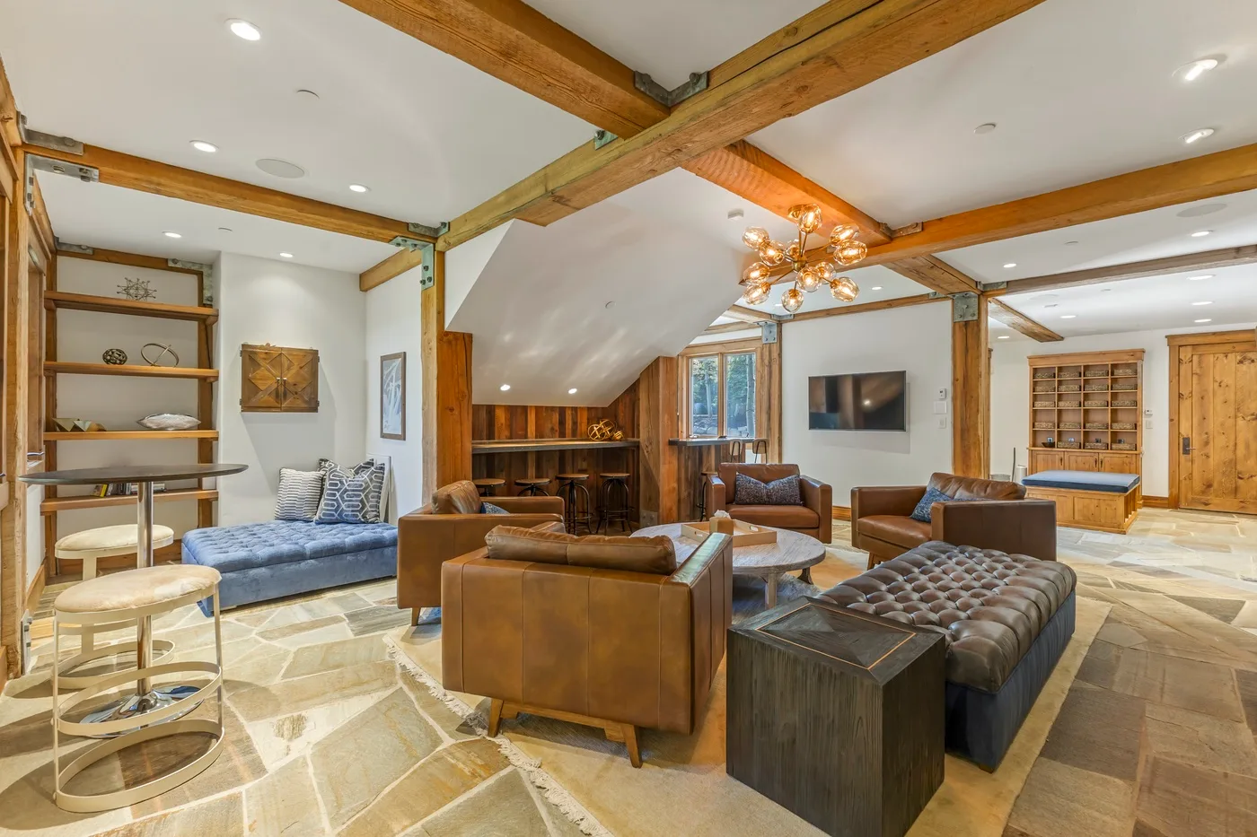 A spacious living room with exposed wooden beams and several seating areas.