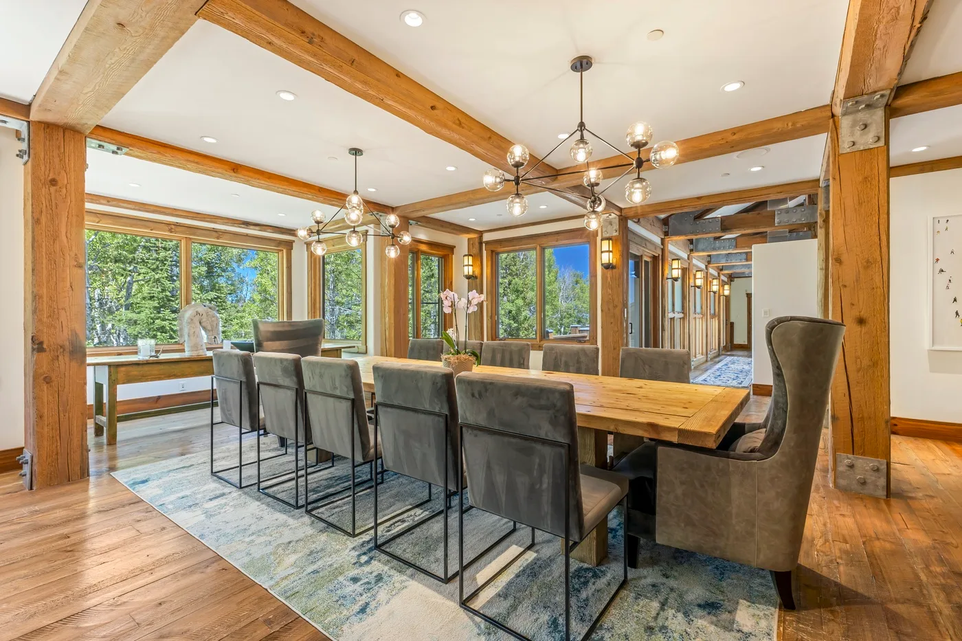 A dining area with a long wooden table and chairs beneath exposed beams.