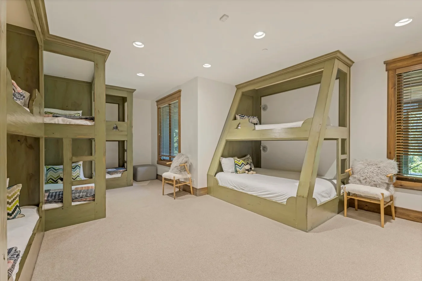 A bedroom with built-in bunk beds, a low bed, and windows.