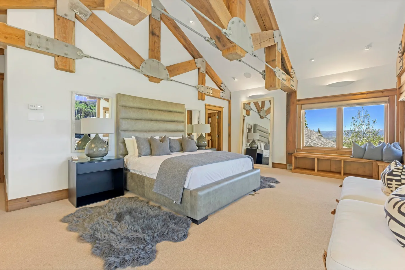 A spacious bedroom with a large bed beneath exposed wooden beams.