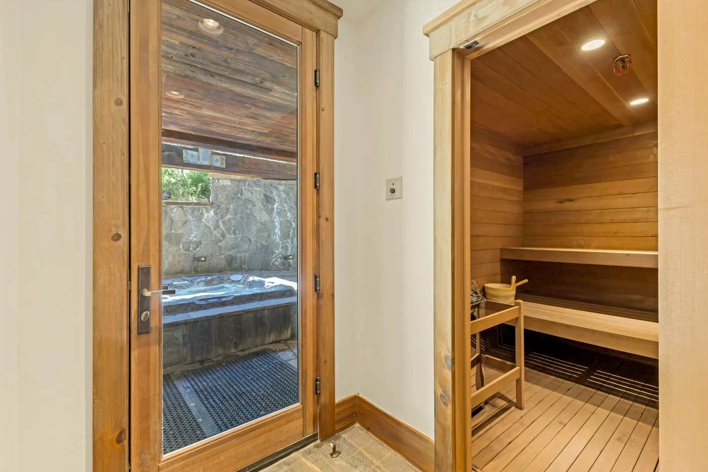 A wood-paneled sauna room with a glass door overlooking an outdoor hot tub.
