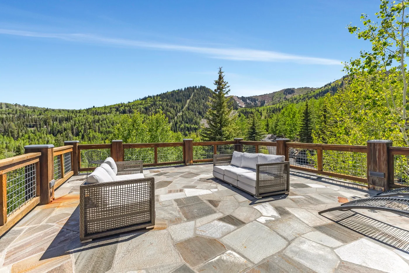 An outdoor deck with seating overlooks a green mountain landscape.