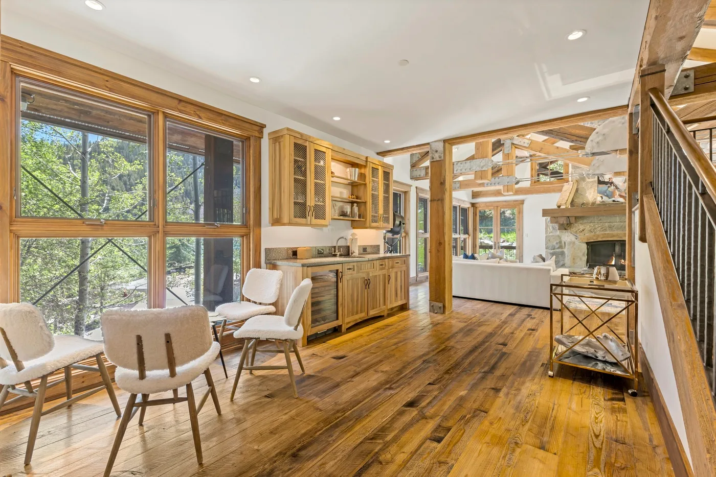 A bright open living area with large windows, seating, and a wood floor.