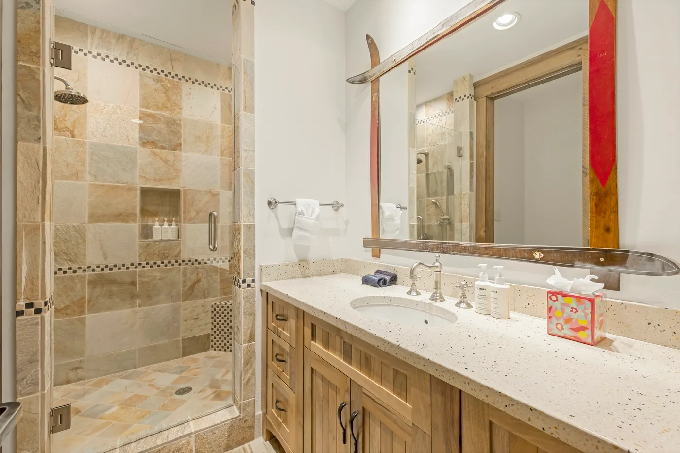 A bathroom vanity with a sink stands beside a tiled shower.