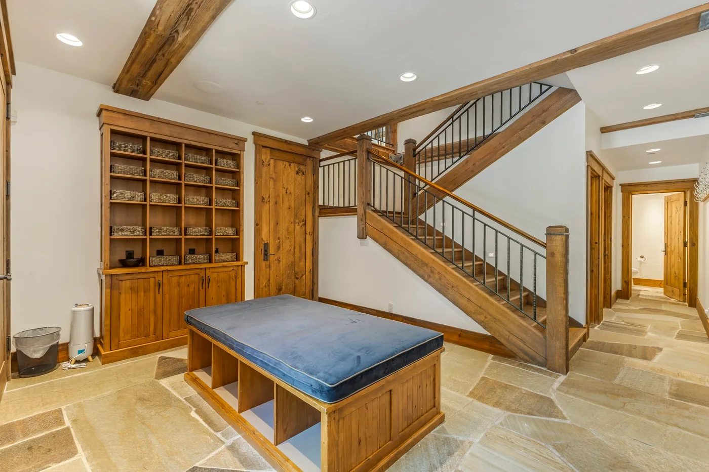 A basement recreation area features a wooden game table beneath a staircase.