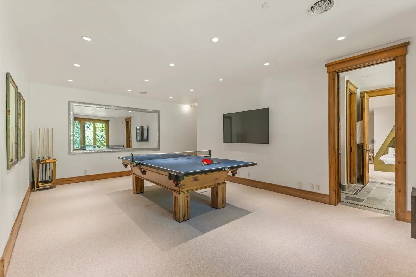 A recreation room with a pool table and a television mounted on the wall.