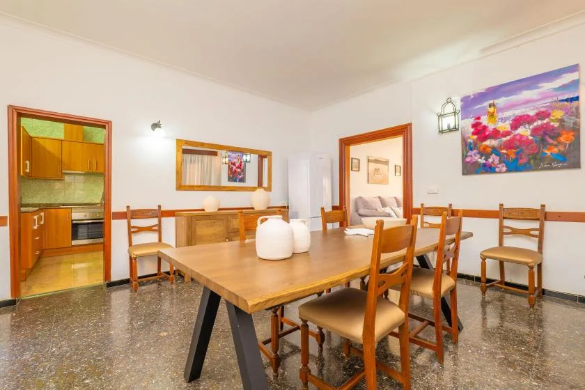 A dining area with a wooden table and chairs beside an open kitchen.