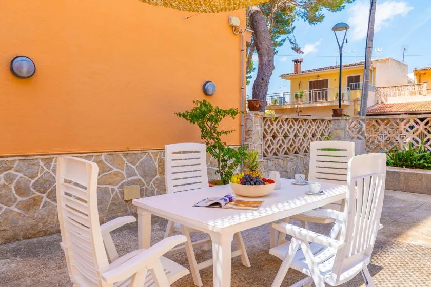 An outdoor patio dining area with a white table and chairs.