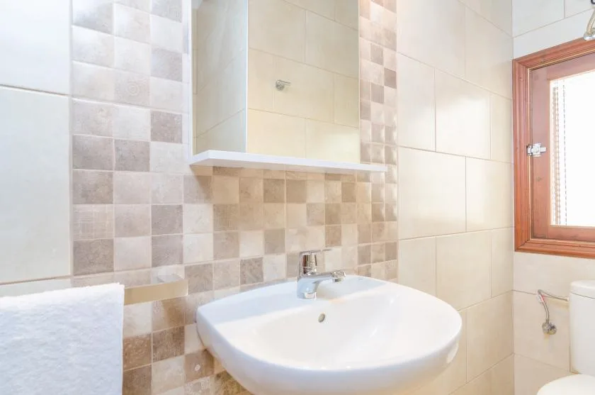 A tiled bathroom with a white sink beneath a wall mirror.