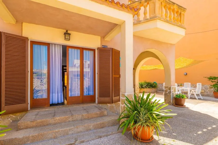 A sunlit patio with sliding glass doors, an arched passage, and outdoor seating.