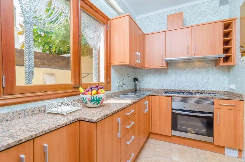 A kitchen with wooden cabinets, a countertop, and a window overlooking greenery.
