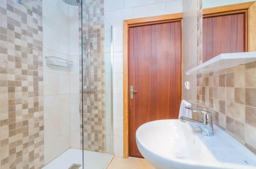A tiled bathroom with a glass shower and a white sink.