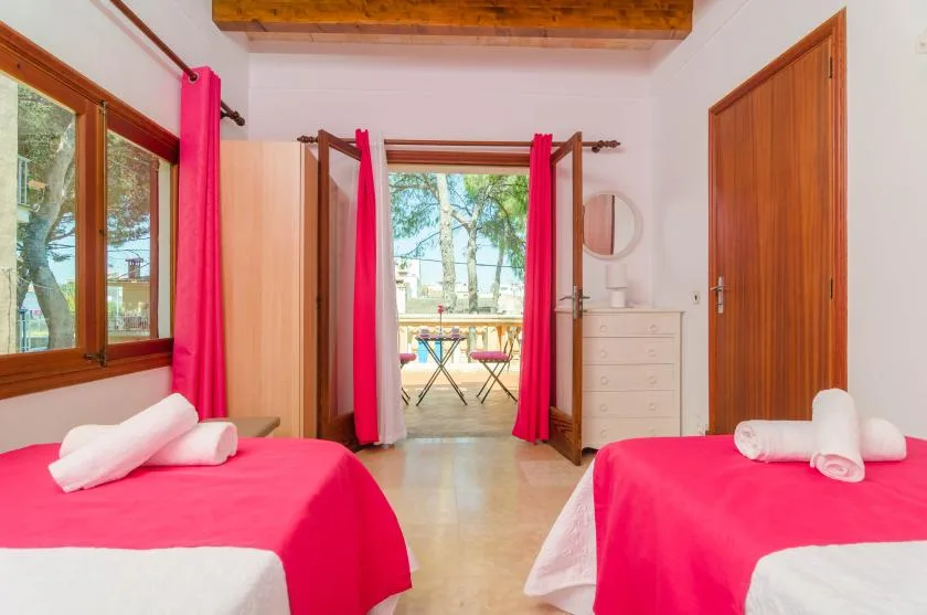 A bedroom with two beds covered in bright pink bedding and a window overlooking trees.