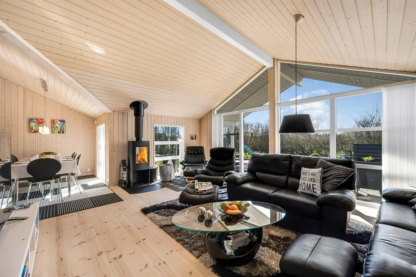 A bright living and dining area with large windows and dark seating.