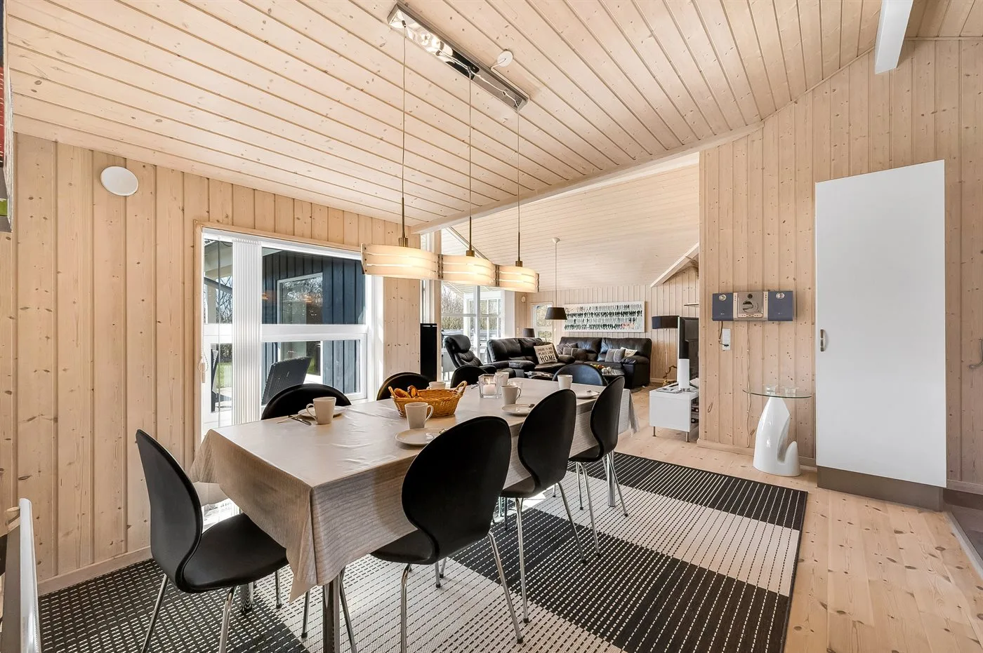 Dining area with a long table and chairs beside the living area.