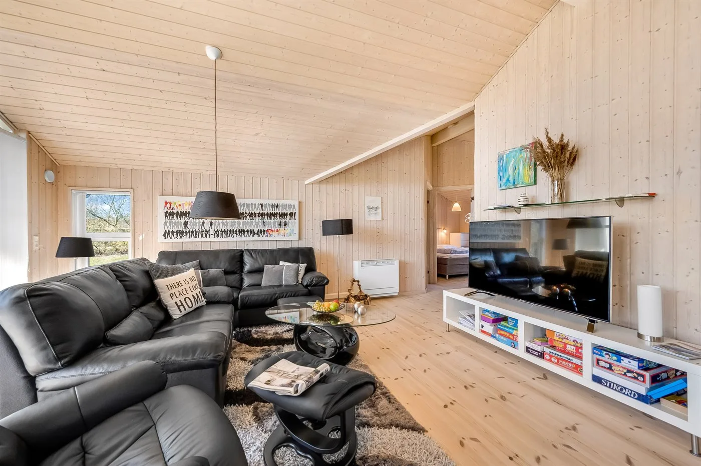 Una sala de estar con asientos oscuros y un televisor sobre un mueble bajo.