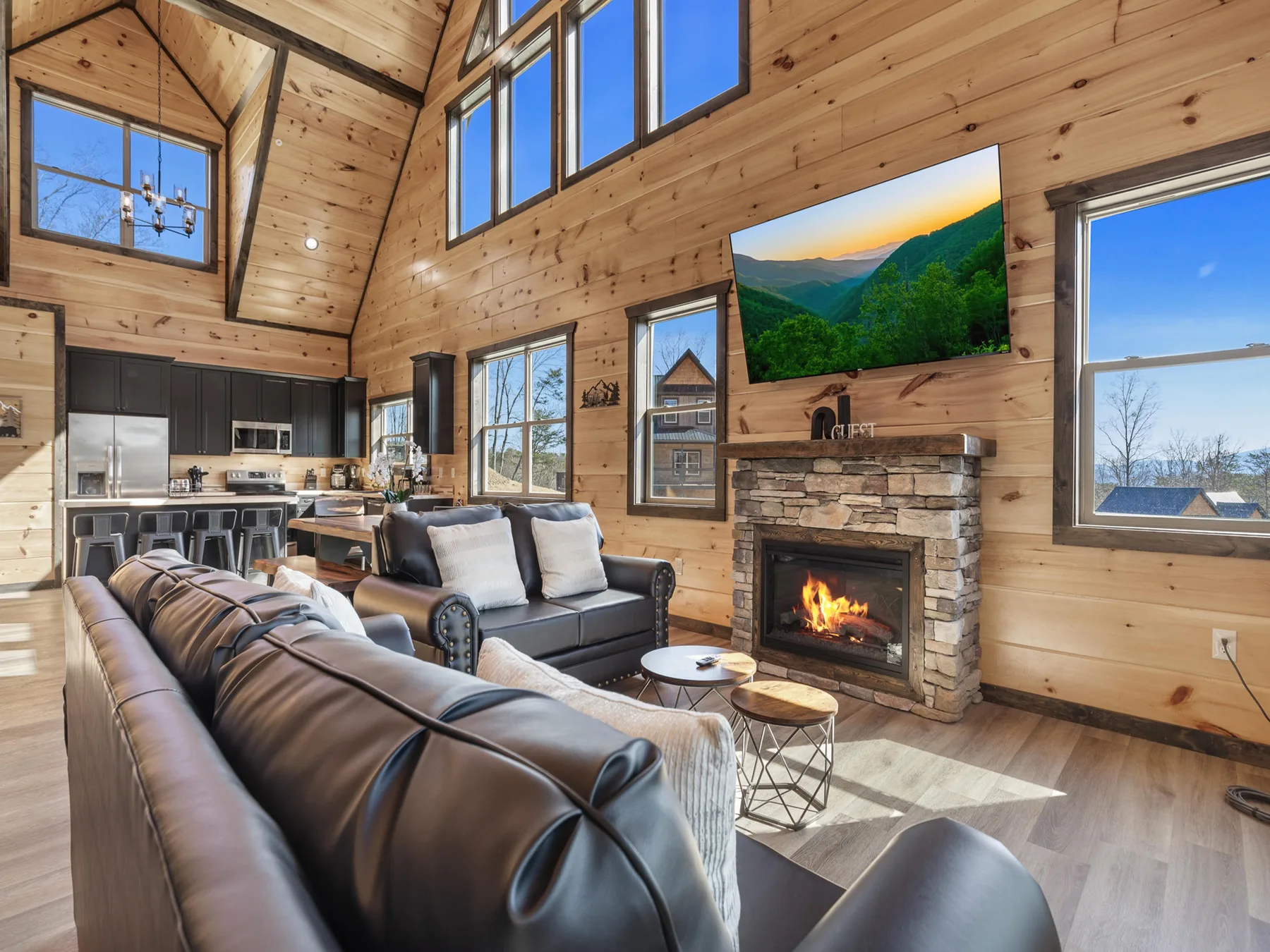 A wood-paneled living room with seating and a stone fireplace.