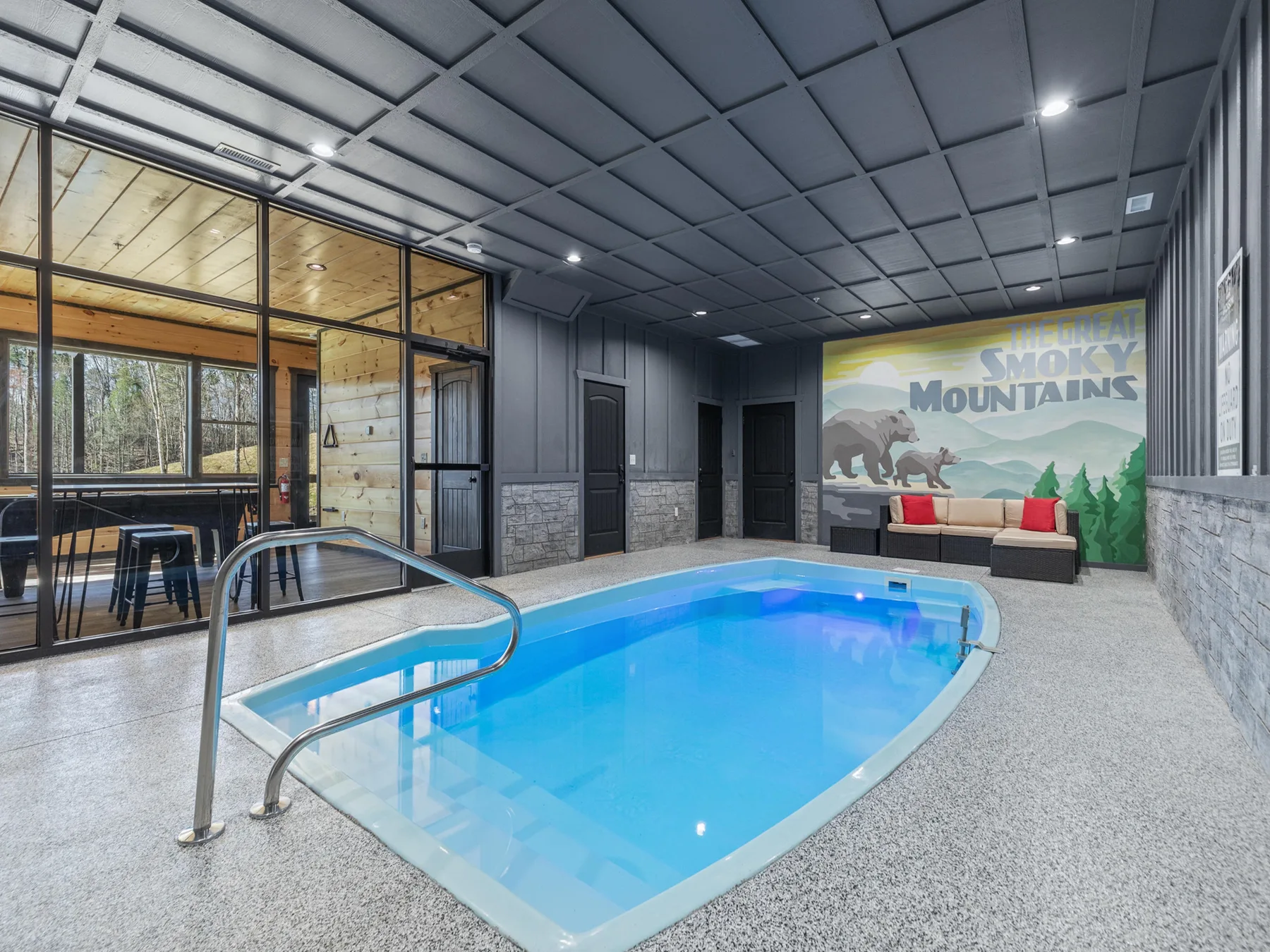 An indoor swimming pool sits beside a glass-walled seating area.